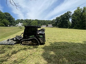 Brush mower on a track loader mowing a field in Chester Springs
